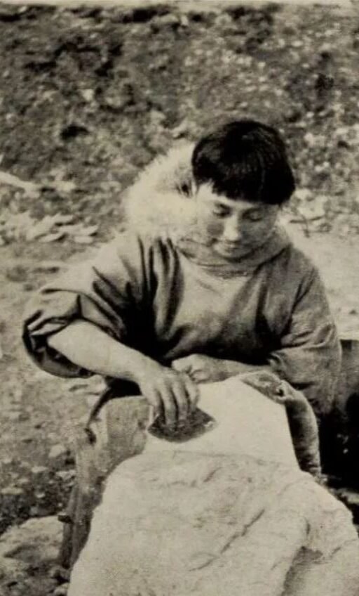 Ada Blackjack using an ulu to scrape blubber from a sealskin